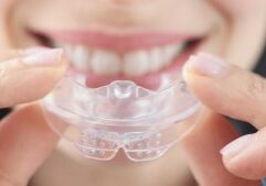 smiling-woman-holds-clear-plastic-mouthguard-straighten-teeth-stafford-dental-clinic